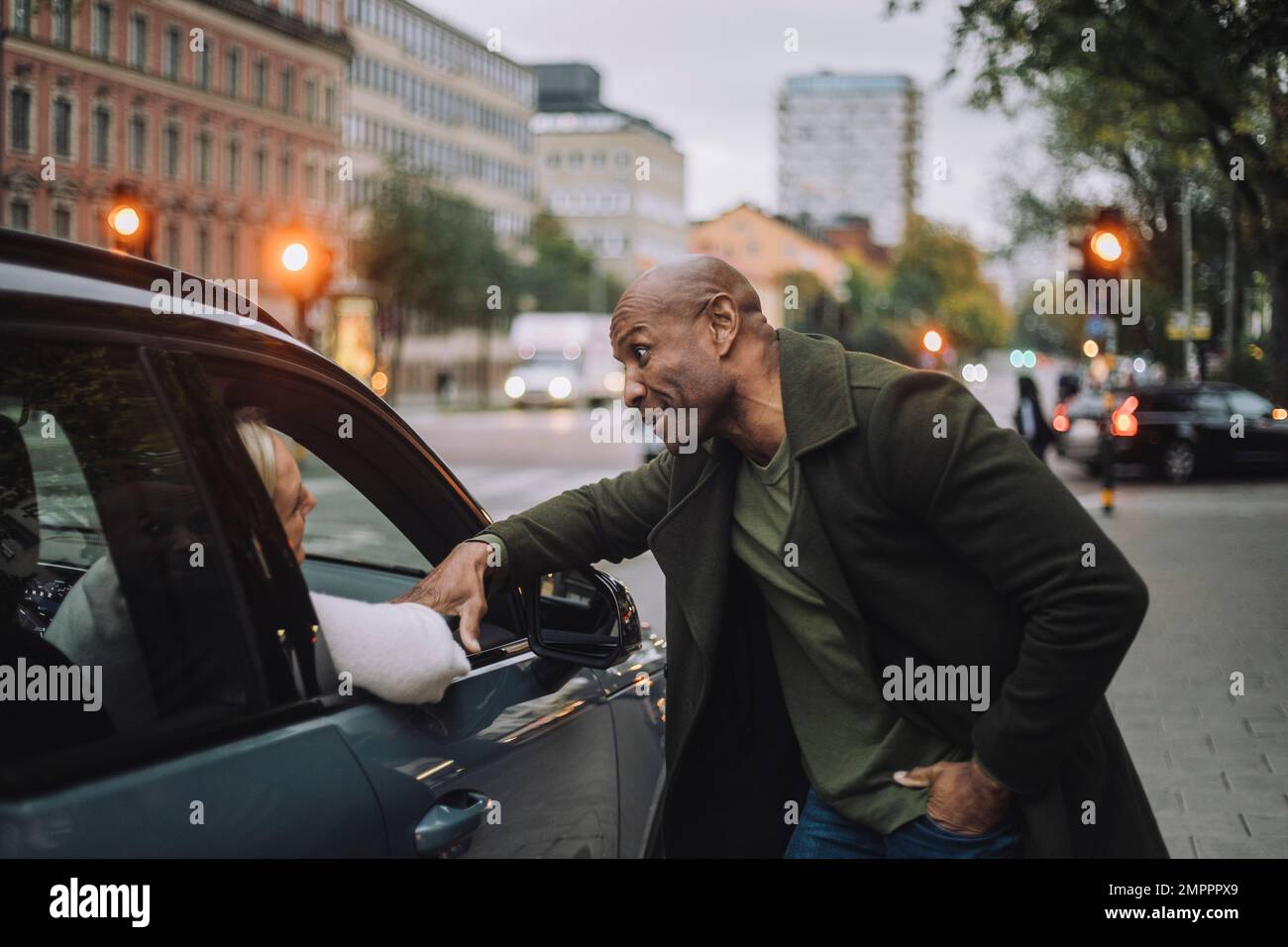 Kahlköpfiger reifer Mann, der mit einer Frau im Auto redet Stockfoto