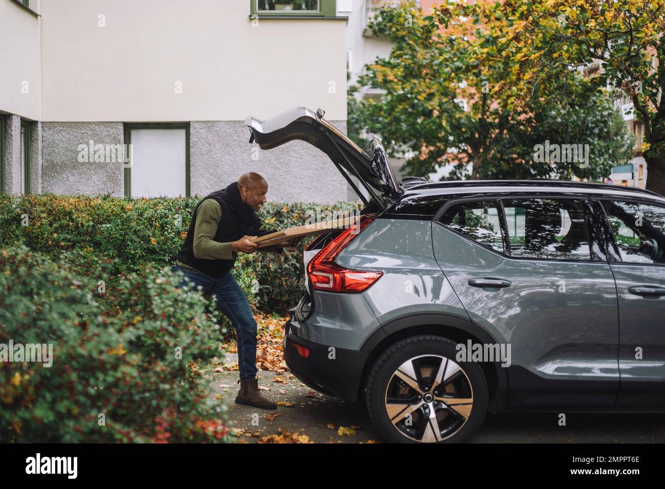 Mann, der beim Umzug des Hauses Pappkartons in den Kofferraum lädt Stockfoto