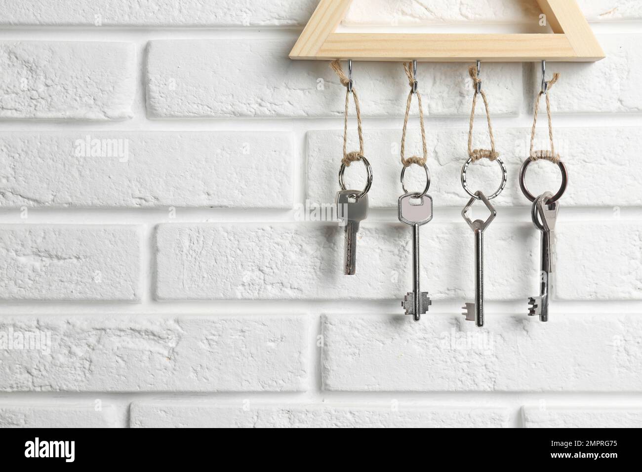 Schlüsselhalter aus Holz an weißen Backsteinwänden im Innenbereich, Nahaufnahme. Platz für Text Stockfoto
