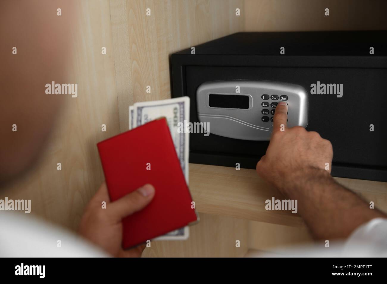 Mann öffnet schwarzen Stahlsafe mit elektronischem Schloss im Hotel, Schließung Stockfoto