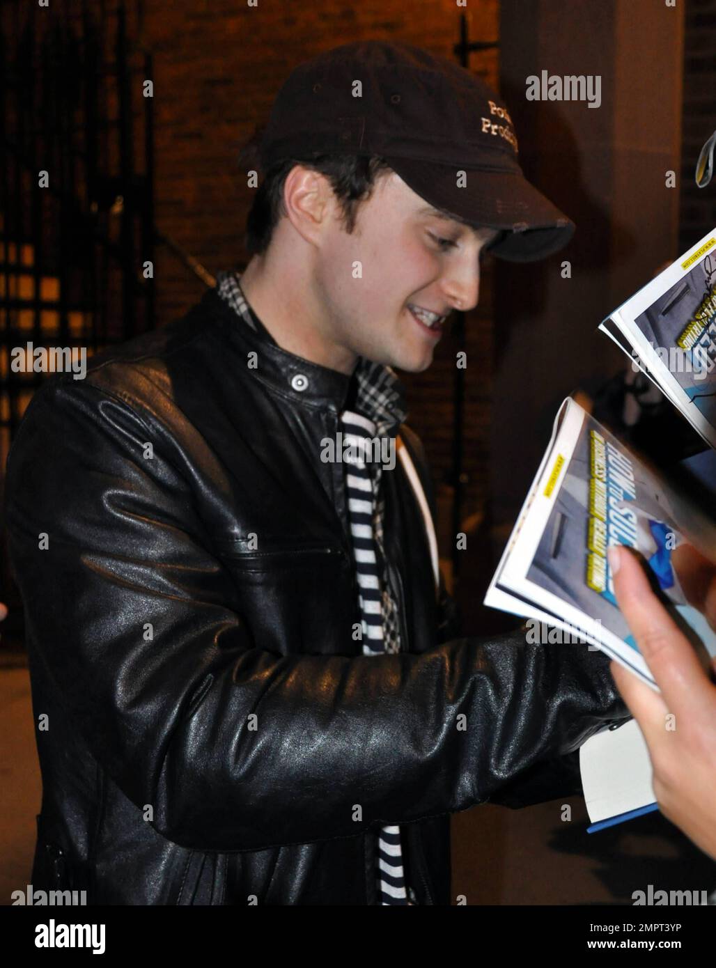 Daniel Radcliffe trägt einen Hut und eine Lederjacke, während er vor dem Al Hirschfeld Theatre Autogramme für wartende Fans signiert, nachdem er seine Aufführung in der Musical-Komödie „How to Success in Business Without really try“ verfolgt hat. New York, NY. 04/02/11. Stockfoto