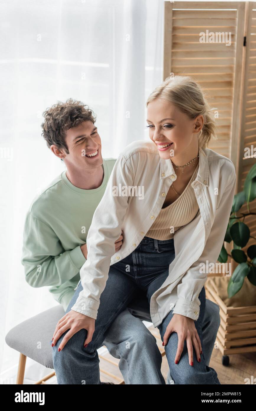 Zufriedene junge Frau, die mit ihrem glücklichen Freund auf der Bettbank sitzt, Bild der Aktie Stockfoto