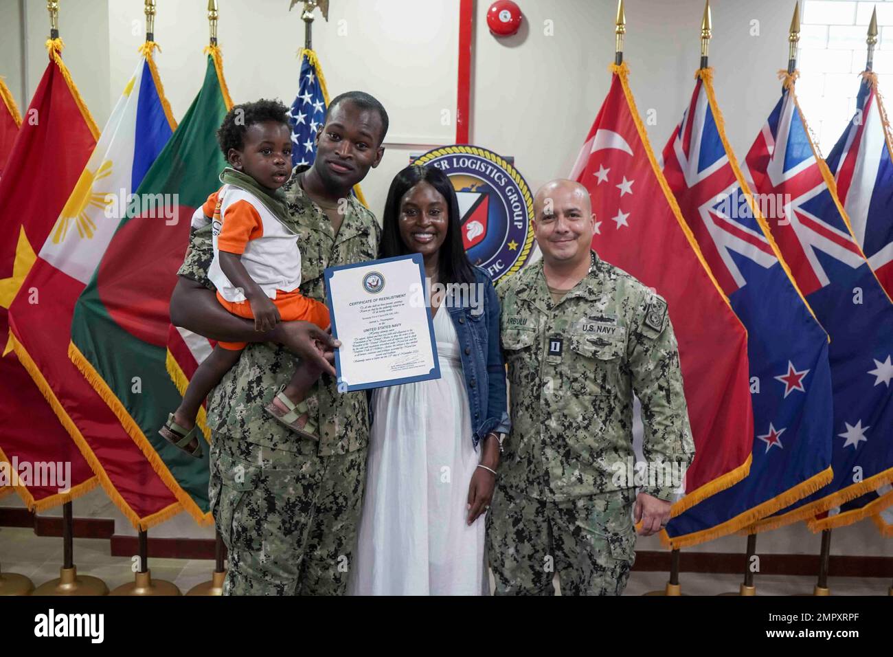 221124-N-JC800-0030 SINGAPUR (24. November 2022) - (von links) Yeoman 1. Klasse Jamal Thompson und Familie zusammen mit LT. Gerardo Arbulubarandiaran, Verwaltungsbeamter des Befehlshabers, Logistics Group Western Pacific/Task Force 73, machen Sie ein Foto während einer Wiedereingliederungszeremonie am 24. November. Stockfoto
