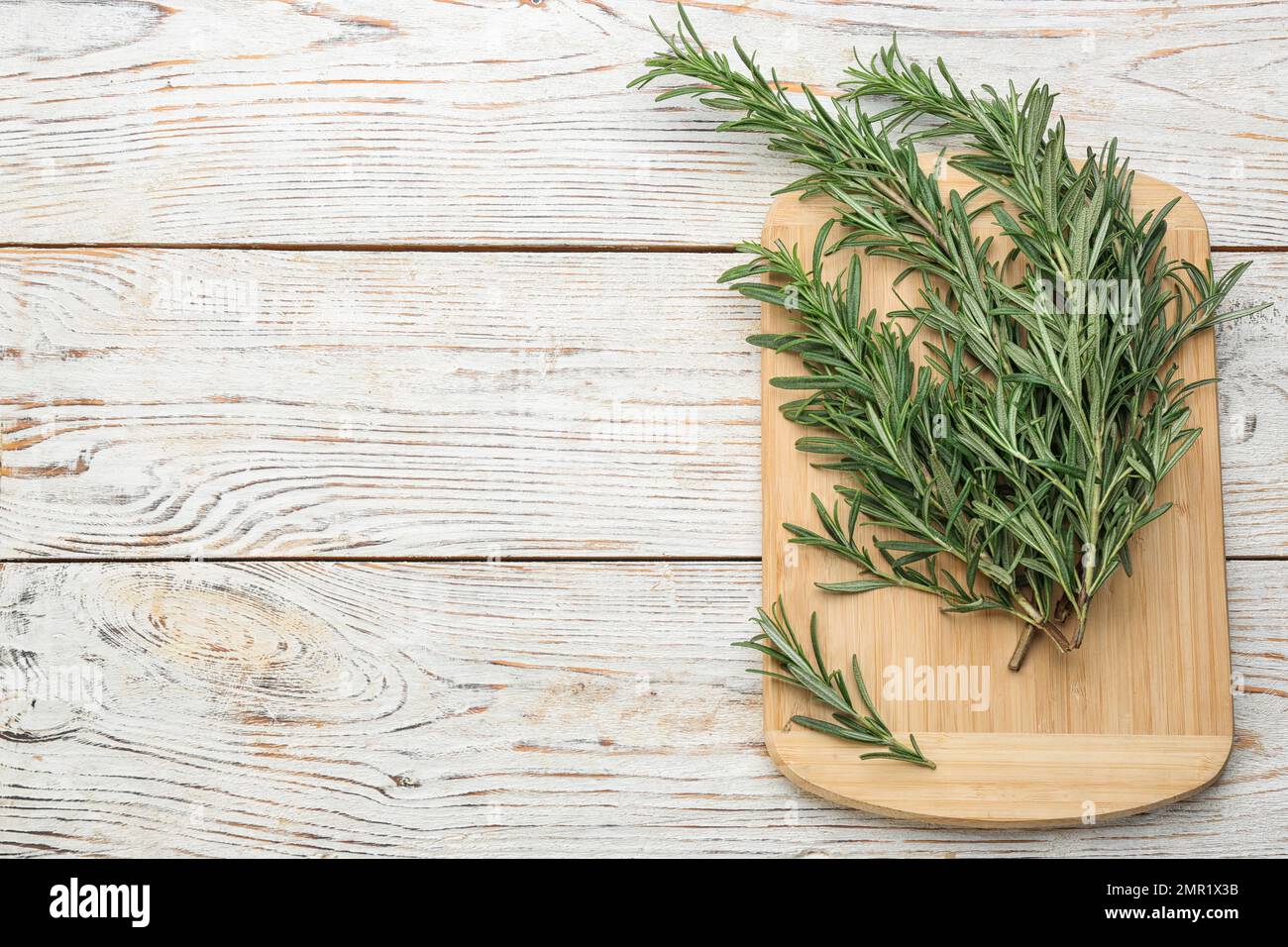 Ein Haufen frischer Rosmarin auf einem weißen Holztisch, von oben. Platz für Text Stockfoto