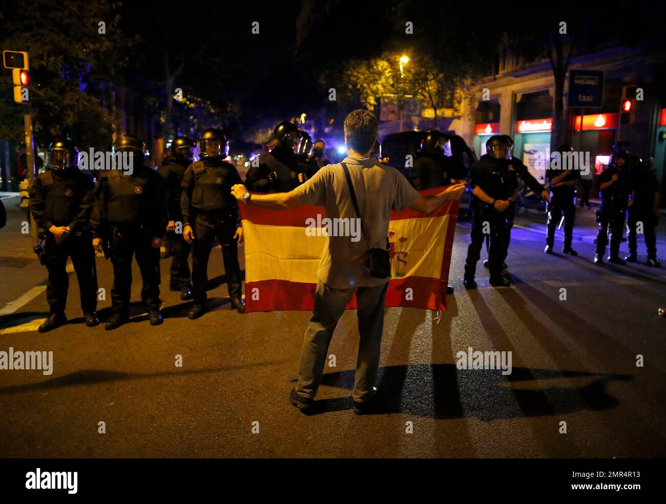 A demonstrator holds a Spanis flag in front of a line of Catalan riot police as anti-independence supporters march against the unilateral declaration of independence approved earlier by the Catalan parliament in downtown Barcelona Friday, Oct. 27, 2017. Catalan lawmakers voted Friday to secede from Spain, shortly before Spain's Senate approved a request by the central government to take direct control of Catalonia's affairs. (AP Photo/Manu Fernandez) Stockfoto