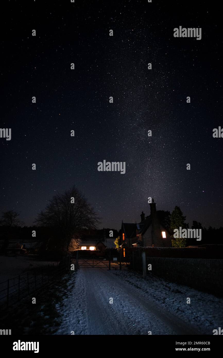 Die Milchstraße erhebt sich über einigen Hütten in einer winterlichen Nachtlandschaft Stockfoto