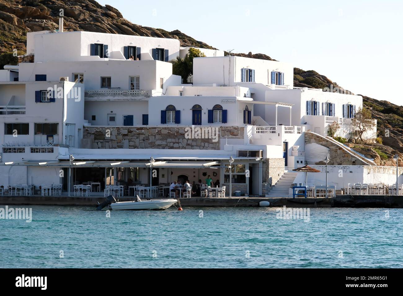 IOS, Griechenland - 3 . Juni 2021 : Blick auf ein weiß getünchtes Hotel und eine Meeresfrüchte-Taverne vor dem berühmten Mylopotas-Strand in iOS Greece Stockfoto