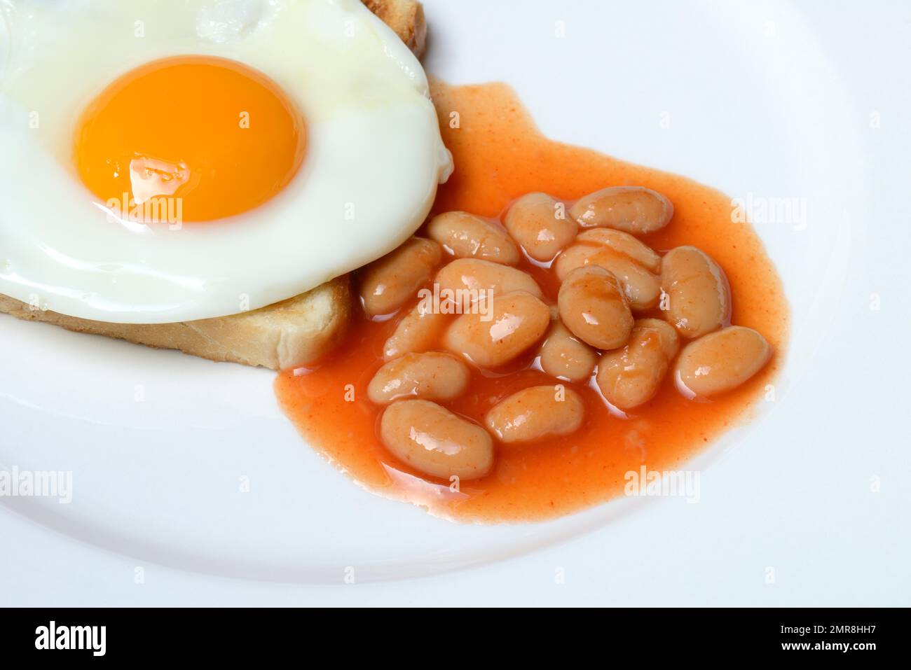 Weiße Bohnen mit Tomatensoße und Spiegelei auf Toast Stockfoto
