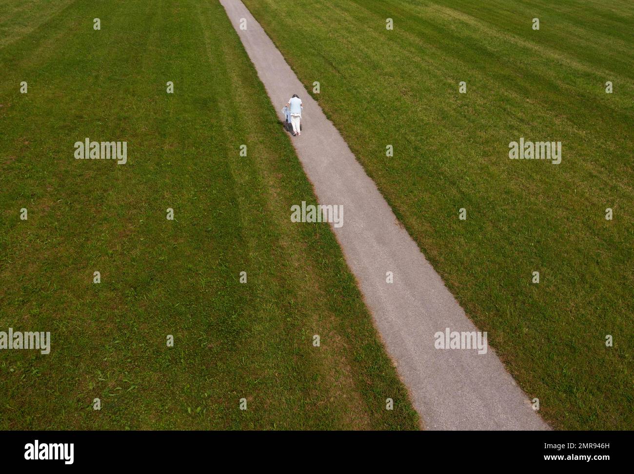 Gebrechliche Frau, die mit einem Roller einen schmalen Pfad entlang läuft, Pfaffing, Hausruckvierel, Oberösterreich, Österreich, Europa Stockfoto
