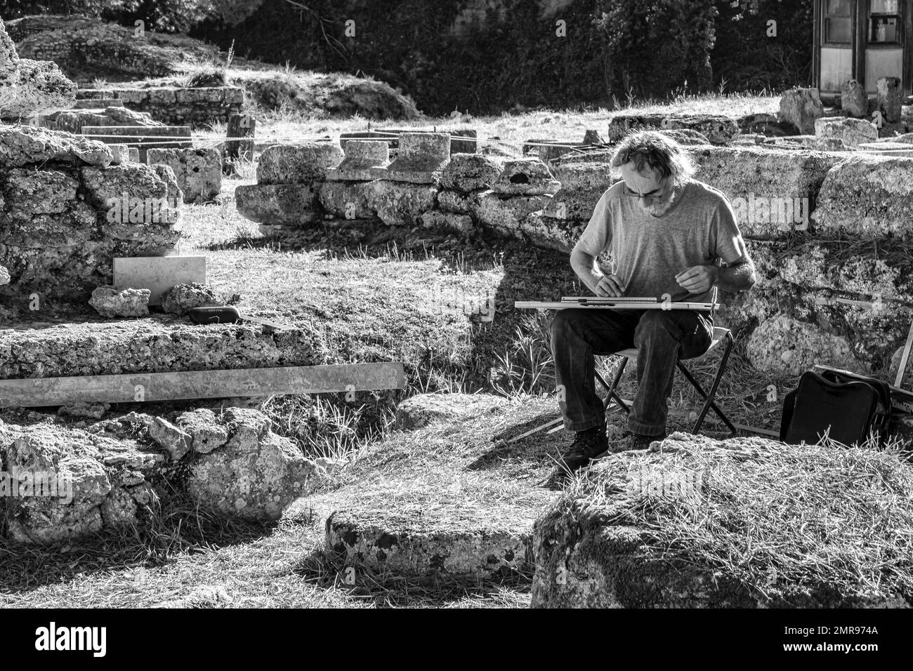 Bei der Arbeit, Schwarzweißbild eines einsamen Mannes, der an der alten Stätte Olympia Griechenland arbeitet Stockfoto