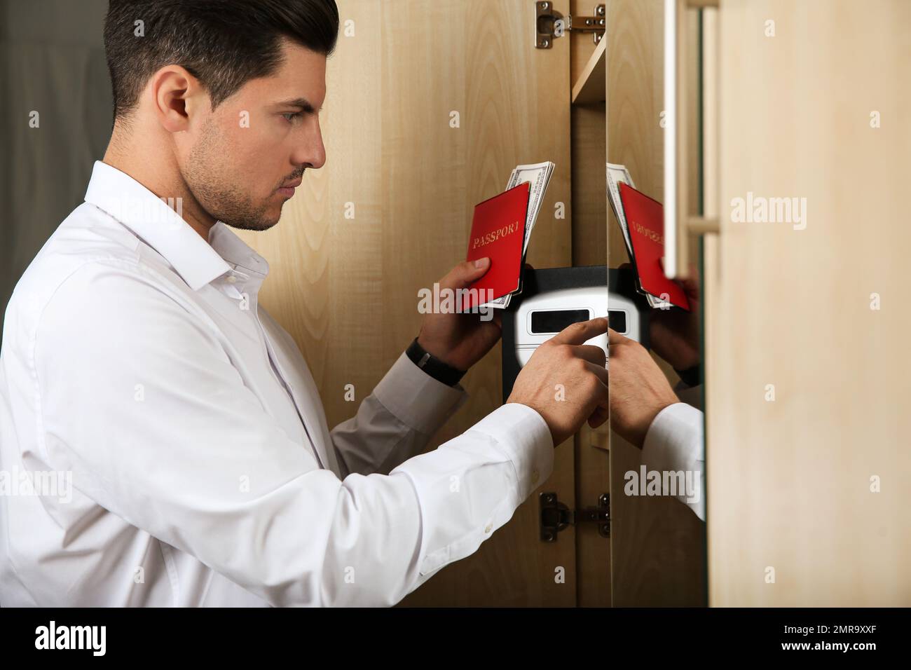 Mann öffnet schwarzen Stahlsafe mit elektronischem Schloss im Hotel Stockfoto