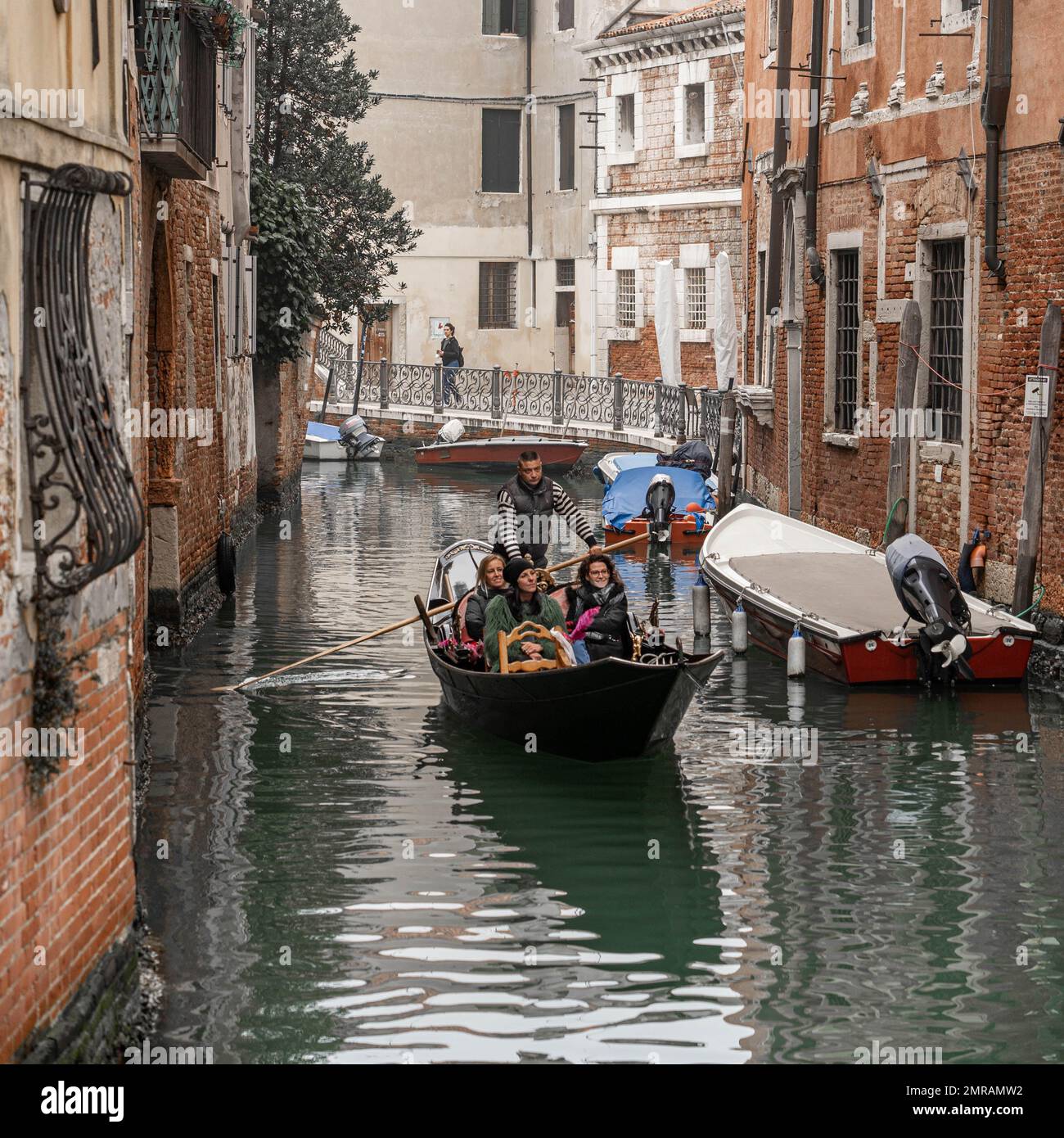 Die Gondel mit den Touristen fließt im Winter am engen Kanal in Venedig, Italien Stockfoto