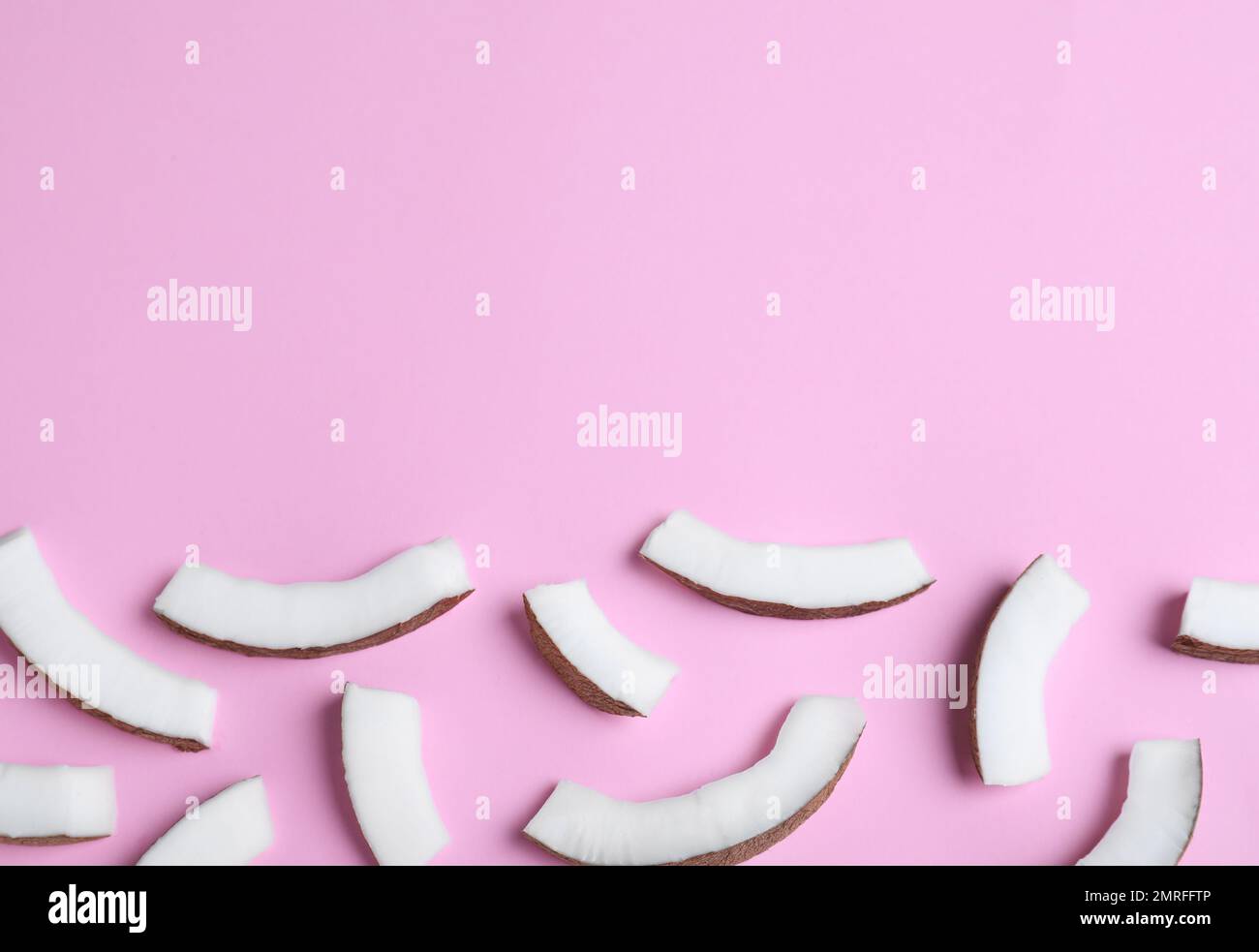 Frische Kokosnussteile auf pinkfarbenem Hintergrund, flach liegend. Platz für Text Stockfoto