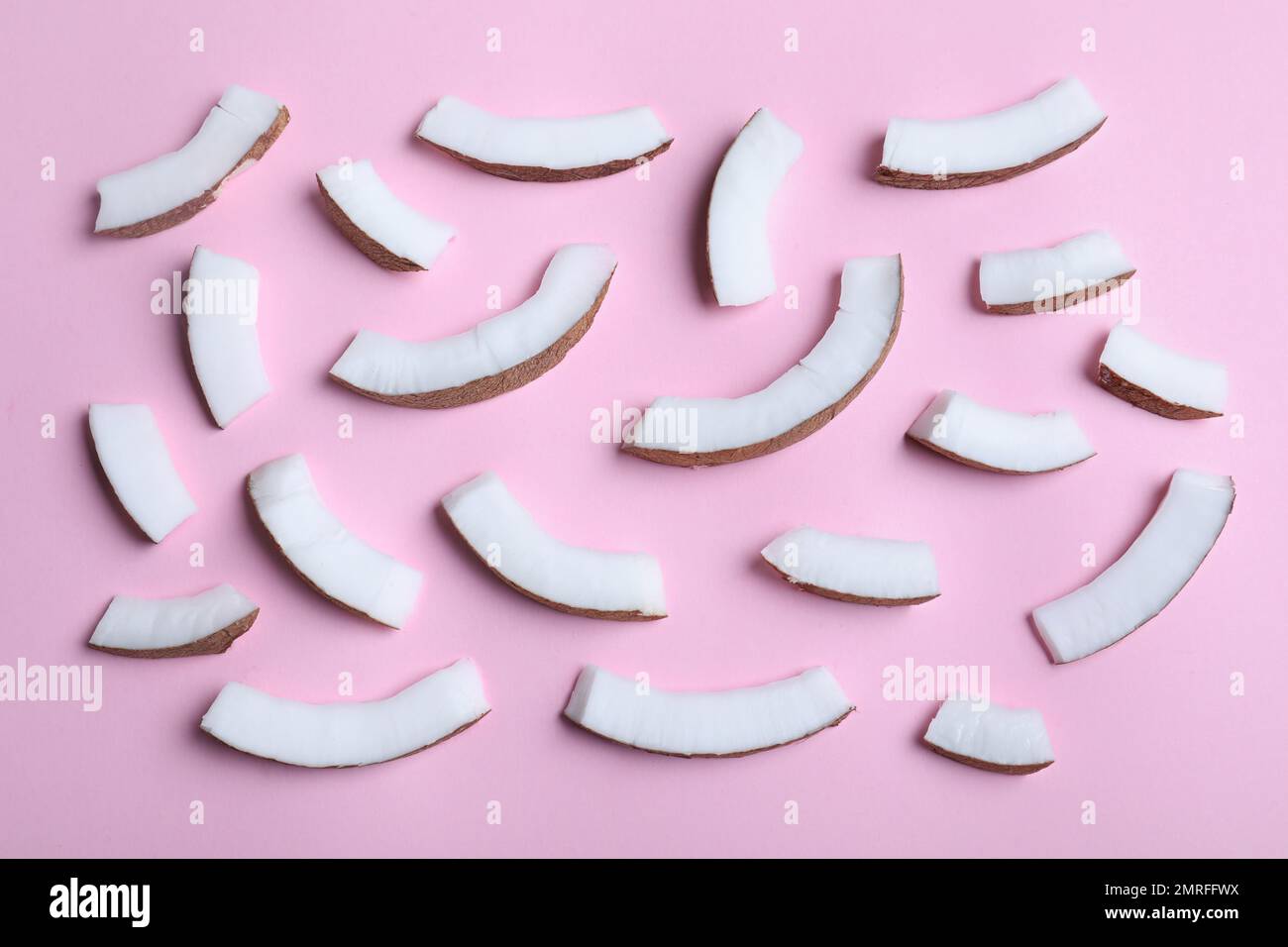 Frische Kokosnussteile auf pinkfarbenem Hintergrund, flach liegend Stockfoto