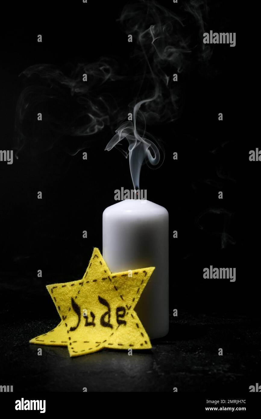 Kerze und jüdisches Abzeichen auf dunklem Hintergrund. Internationaler Holocaust-Gedenktag Stockfoto