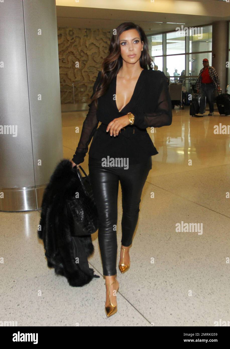 Kim Kardashian wurde gesehen, wie er am Miami International Airport ankam, um einen Flug aus der Stadt zu erwischen. Kim trug ein schwarzes, transparentes Oberteil mit schwarzen Lederhosen und goldenen hohen Absätzen und trug eine große schwarze Handtasche und eine schwarze pelzige Jacke. Miami, Florida 17. Oktober 2012. Stockfoto
