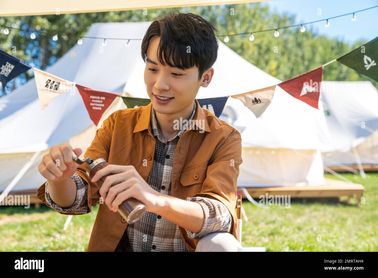 Der Junge, der unter der Markise sitzt und Kaffee mahlt Stockfoto