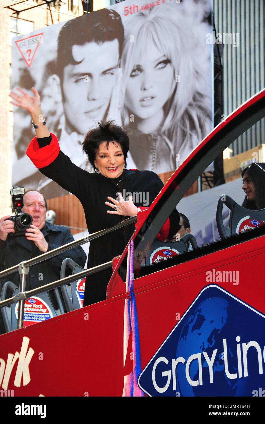 Die erfahrene Künstlerin und Sängerin Liza Minnelli schneidet das Band, winkt fröhlich vom Oberdeck eines Gray Line New York Sightseeing Tours Busses und posiert für Fotografen bei der Zeremonie zum Schneiden von Bändern, die sie am Times Square ehrt. New York, NY. 03/08/11. Stockfoto