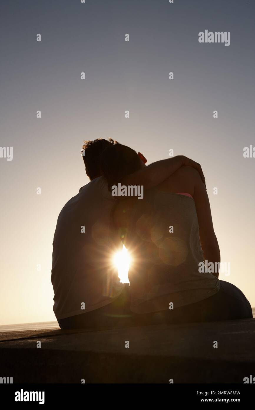 Das ist Liebe... Silhouette von einem Paar, das draußen nebeneinander sitzt. Stockfoto