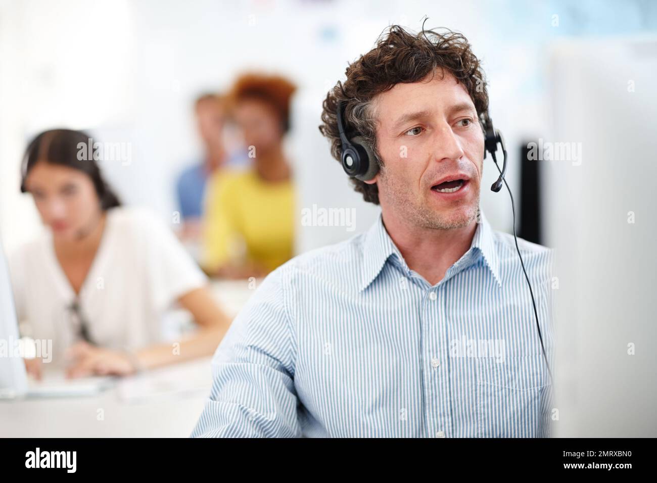 Ich rede mit einem Kunden. Ein attraktiver Callcenter-Mitarbeiter im Büro. Stockfoto