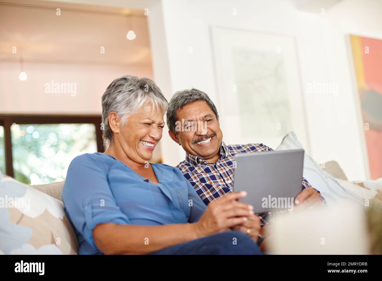Technisch versierte Senioren. Ein glückliches Seniorenpaar, das zu Hause zusammen ein digitales Tablet verwendet. Stockfoto