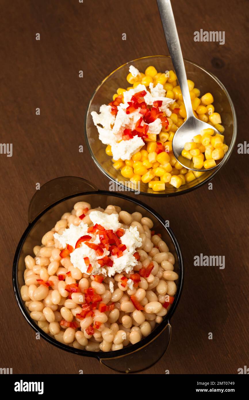 Esquites mit Mais und weißen Kidney Beans, Käse, Mayonnaise und Chili auf dunklem Hintergrund. Mexikanisches Street Food Stockfoto