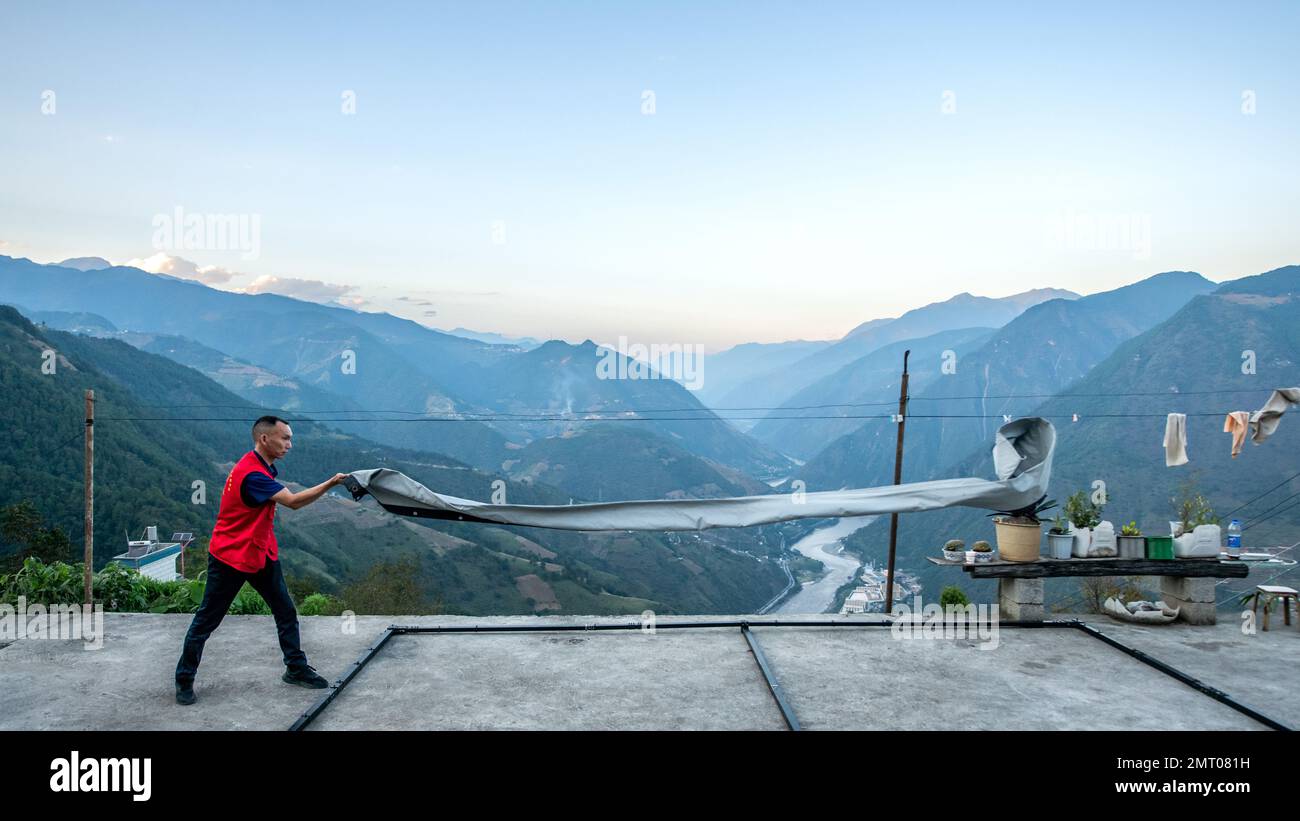 Lushui, Chinas Provinz Yunnan. 21. Okt. 2022. Yang Mingjin öffnet am 21. Oktober 2022 im Dorf Denggeng in der autonomen Präfektur Lisu in Nujiang, Provinz Yunnan im Südwesten Chinas, eine Leinwand. ZUM Beispiel „Profil: Reifenhändler beleuchtet die Berge mit Filmen“. Kredit: HU Chao/Xinhua/Alamy Live News Stockfoto