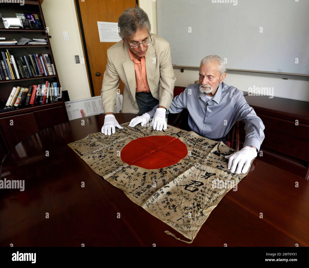In this Monday, Aug. 7, 2017 photo, WWII veteran Marvin Strombo, right, and Obon Society executives director Rex Zika lay out a Japanese flag with names written on it in Portland, Ore. Strombo recovered the flag from a dead Japanese soldier in the Pacific more than 70 years ago and now, at age 93, will return the flag to the Japanese man's surviving siblings. (AP Photo/Don Ryan) Stockfoto
