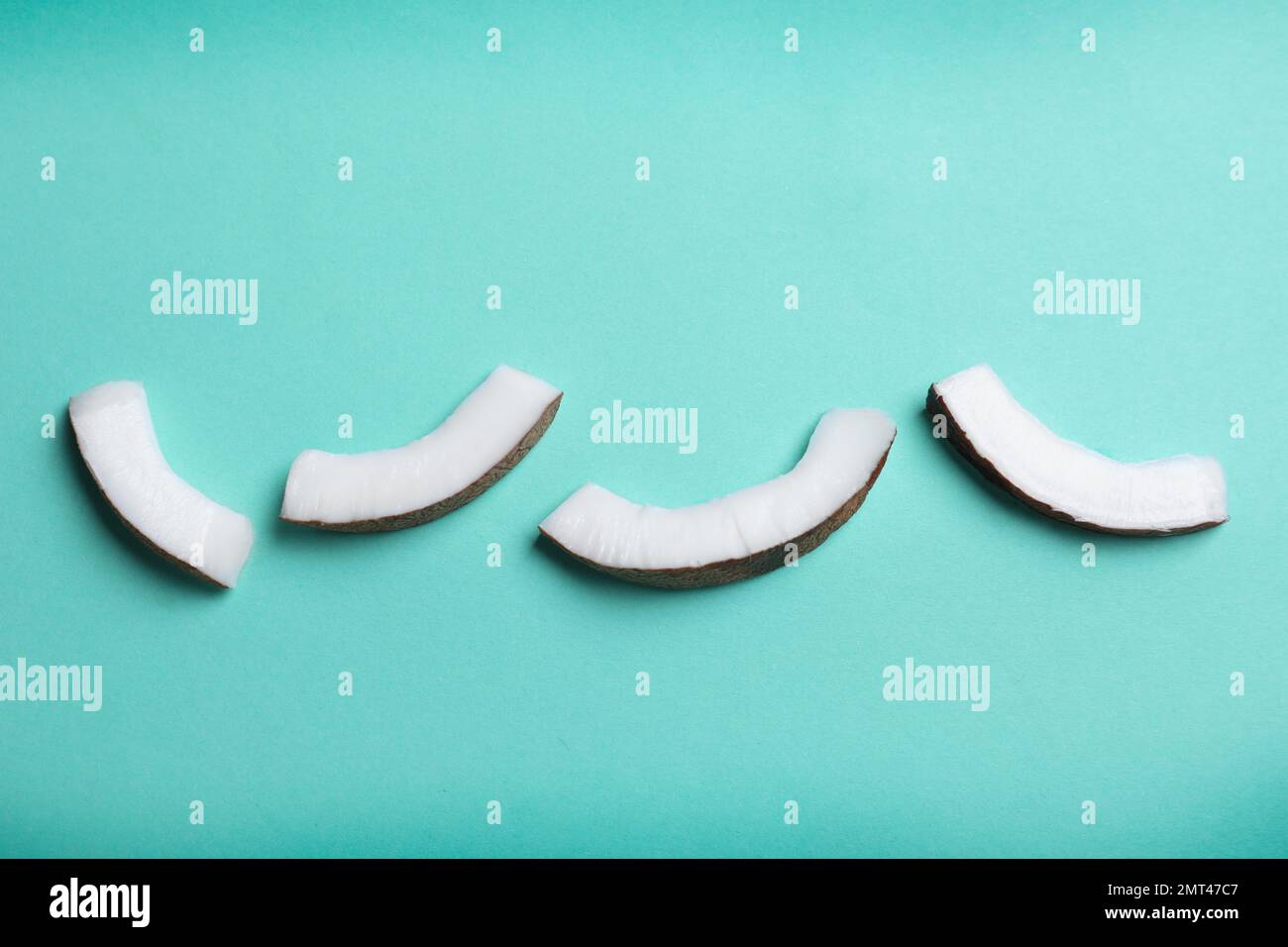 Frische Kokosnussteile auf türkisfarbenem Hintergrund, flach liegend Stockfoto