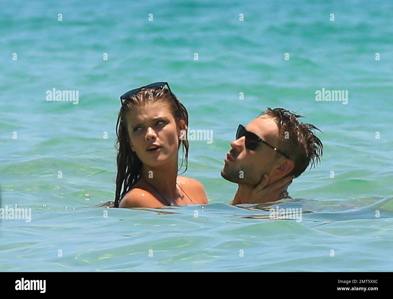 Die sportlich illustrierte Stunnerin Nina Agdal, Ex-Freundin von Max George, wurde mit ihrem neuen Freund gesehen, der sich in Miami am Strand verliebte. Die Schönheit des Bikinis wurde gesehen, wie sie ihren Freund Reid Heidenry küsste und kuschelte und auch ihre Beine im Wasser um ihn wickelte und ihm ins Ohr beißte. Das Paar wurde von einem männlichen Begleiter begleitet, während sie sich lustig machten und sich einen Tennisball zuwarfen. Nina hielt auch an, um mit Devin Brugman zu plaudern. Miami Beach, Florida 19. Juli 2014 Stockfoto