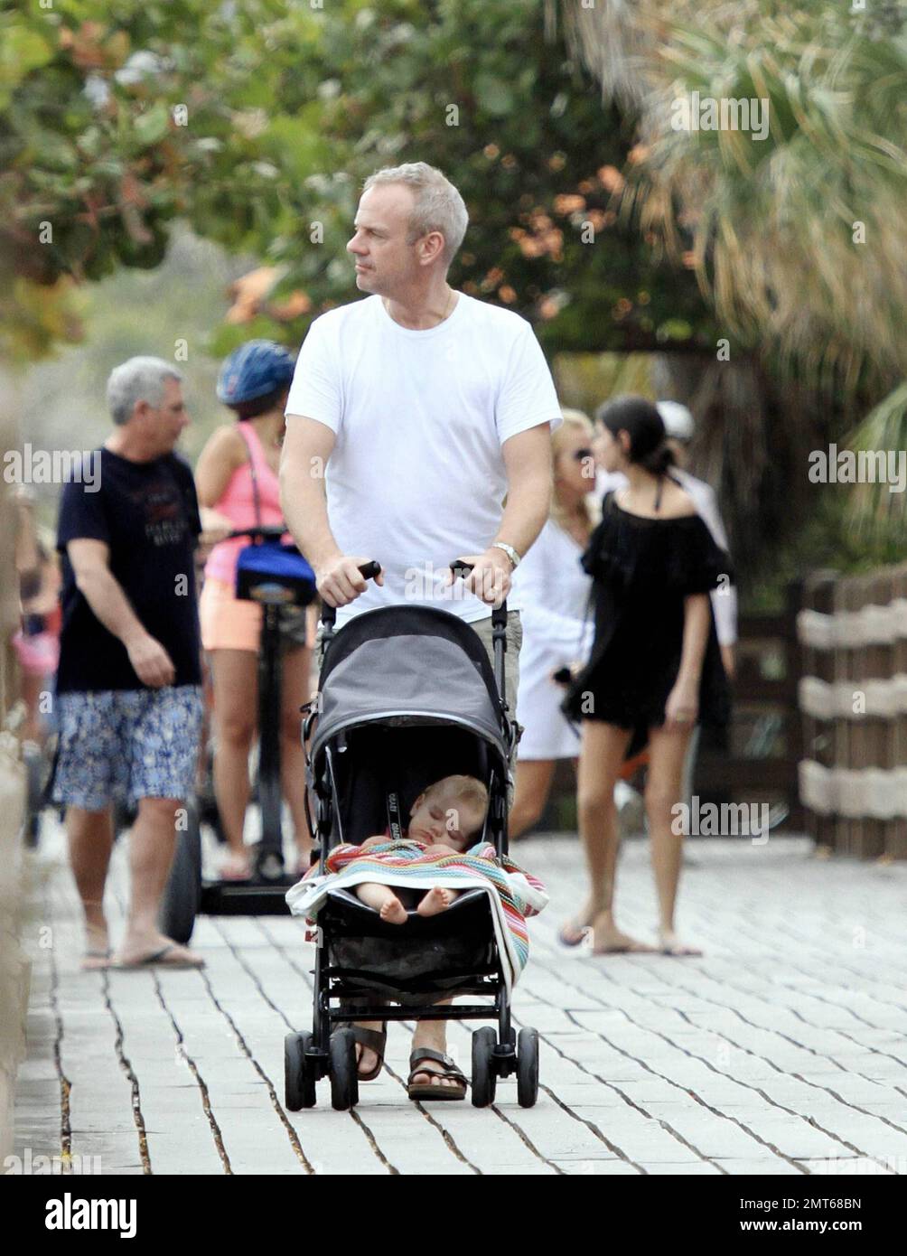 Norman Cook, auch bekannt als DJ Fatboy Slim, verbringt sich mit seiner bezaubernden, neuen Schlafenszeit-Tochter Nelly. Vor seiner Silvestervorstellung in South Beach machte Cook einen gemütlichen Spaziergang auf der Strandpromenade. Miami Beach, Florida 12/30/10. Stockfoto