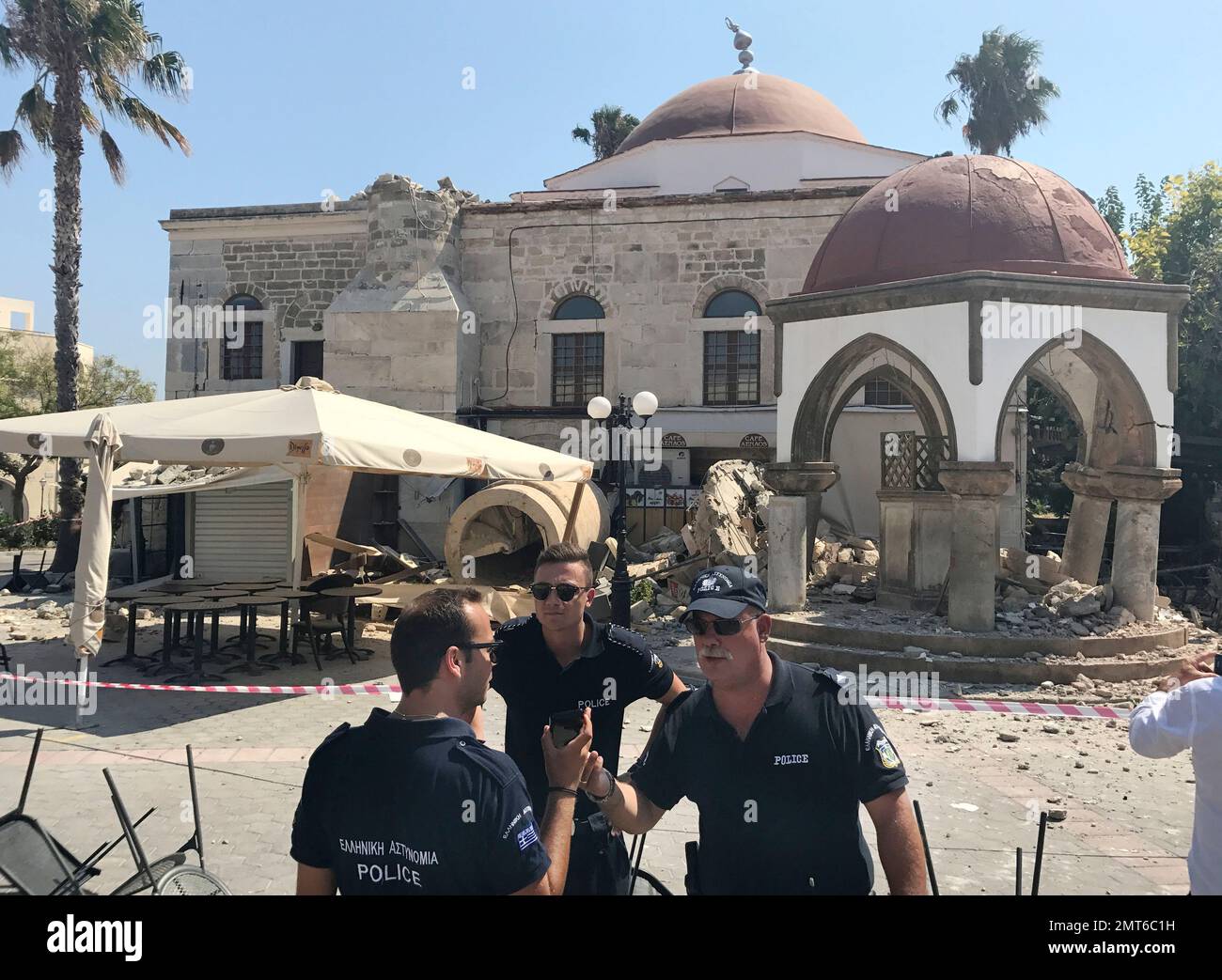 Police officers stand in fron of a partially collapsed mosque after an earthquake in Kos on the island of Kos, Greece Friday, July 21, 2017. Greek authorities said the two tourists who were killed in that house in the overnight quake are from Turkey and Sweden.(AP Photo/Michael Probst) Stockfoto