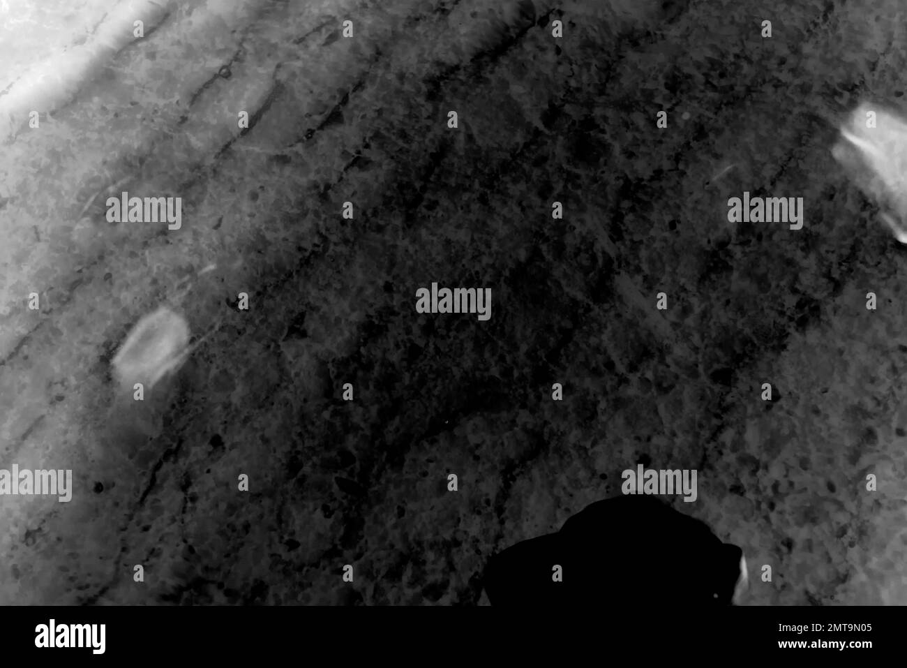 Schwarz-weiß abstraktes Foto der Oberflächenstruktur von transparenten Wasserwellen mit Sand auf einem dunklen Boden. Stockfoto
