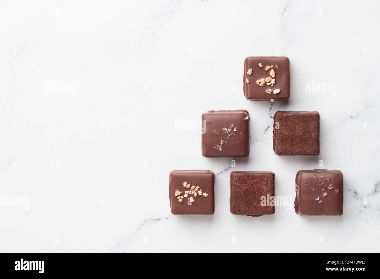 Schokoladenbonbons auf weißem Marmorhintergrund, Blick von oben mit Kopierraum Stockfoto