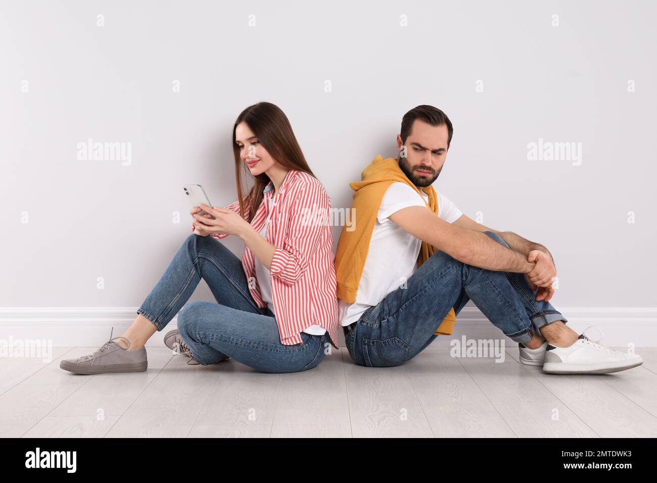 Misstrauischer junger Mann, der in das Smartphone seiner Freundin drinnen schaut. Beziehungsprobleme Stockfoto