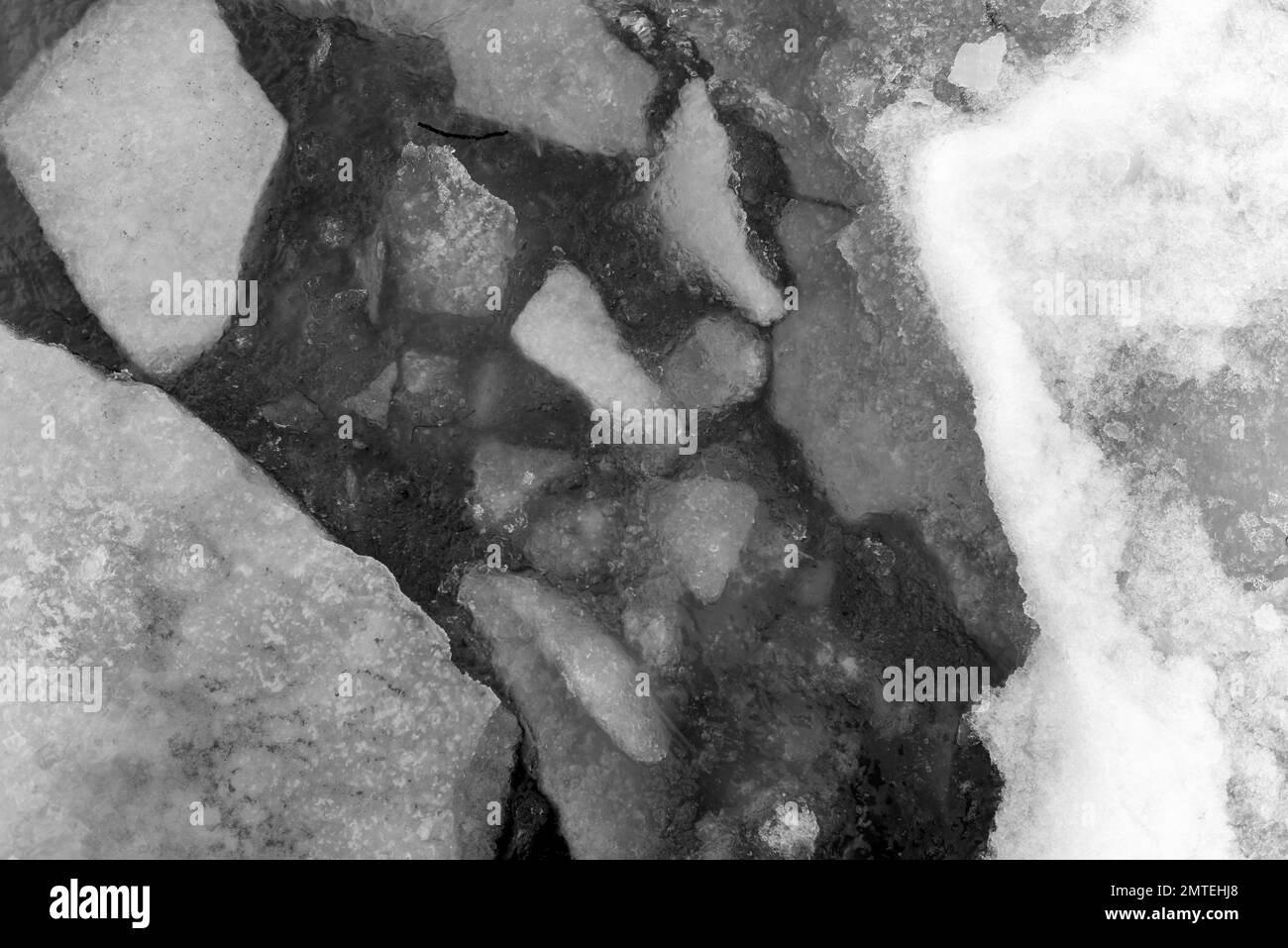 Wassertextur mit Schnee und Eis im Sonnenlicht im Winter. Stockfoto