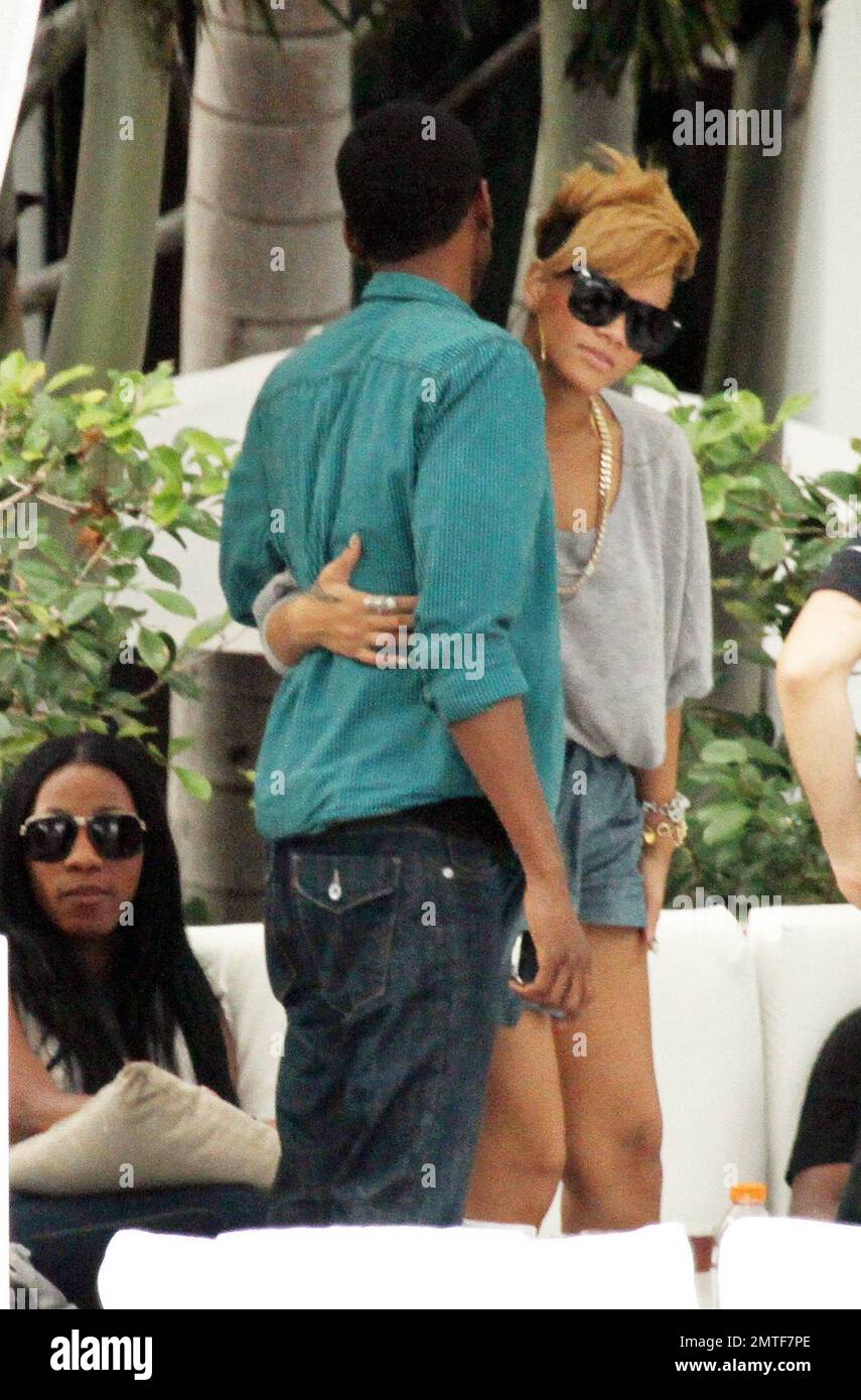 Rihanna wird während eines entspannten Nachmittags am Pool des Fontainebleau Miami Beach umarmt. Der Songstress, der Rosenwein trank, plauderte und lachte mit Freunden in einer privaten Cabana für ein paar Stunden. Rihanna trug ein ganz graues Outfit mit einem T-Shirt, Shorts und Schuhen mit hohen Absätzen und Accessoires mit großen Ohrringen und einer goldenen Halskette. Miami, Florida 2/5/10. Stockfoto