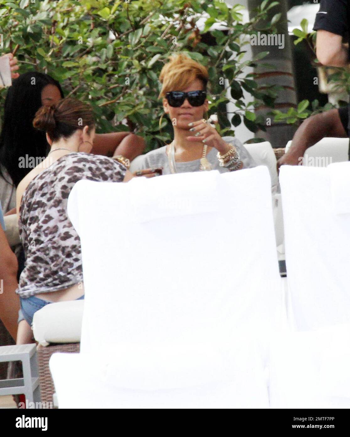 Rihanna wird während eines entspannten Nachmittags am Pool des Fontainebleau Miami Beach umarmt. Der Songstress, der Rosenwein trank, plauderte und lachte mit Freunden in einer privaten Cabana für ein paar Stunden. Rihanna trug ein ganz graues Outfit mit einem T-Shirt, Shorts und Schuhen mit hohen Absätzen und Accessoires mit großen Ohrringen und einer goldenen Halskette. Miami, Florida 2/5/10. Stockfoto