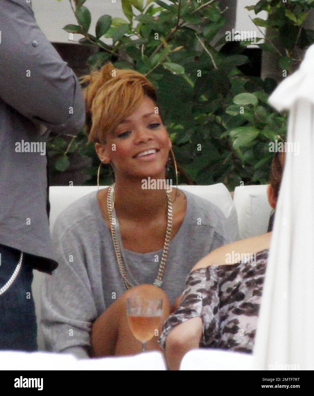 Rihanna wird während eines entspannten Nachmittags am Pool des Fontainebleau Miami Beach umarmt. Der Songstress, der Rosenwein trank, plauderte und lachte mit Freunden in einer privaten Cabana für ein paar Stunden. Rihanna trug ein ganz graues Outfit mit einem T-Shirt, Shorts und Schuhen mit hohen Absätzen und Accessoires mit großen Ohrringen und einer goldenen Halskette. Miami, Florida 2/5/10. . Stockfoto