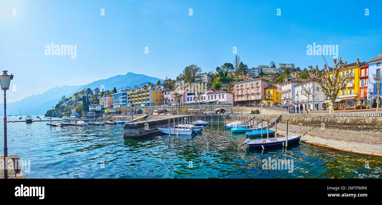 Panoramablick auf den Lago Maggiore mit Blick auf bunte Häuser, Cafés, Restaurants und trübe Berge im Hintergrund, Ascona, Schweiz Stockfoto