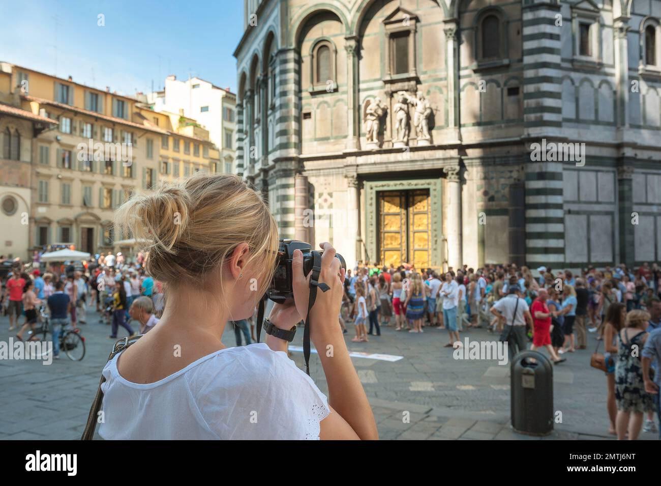 Frau fotografiert, Rückansicht einer jungen Frau mit einer Kamera, die ein Foto des Baptisteriums aus der Renaissance in Florenz, Italien, macht Stockfoto