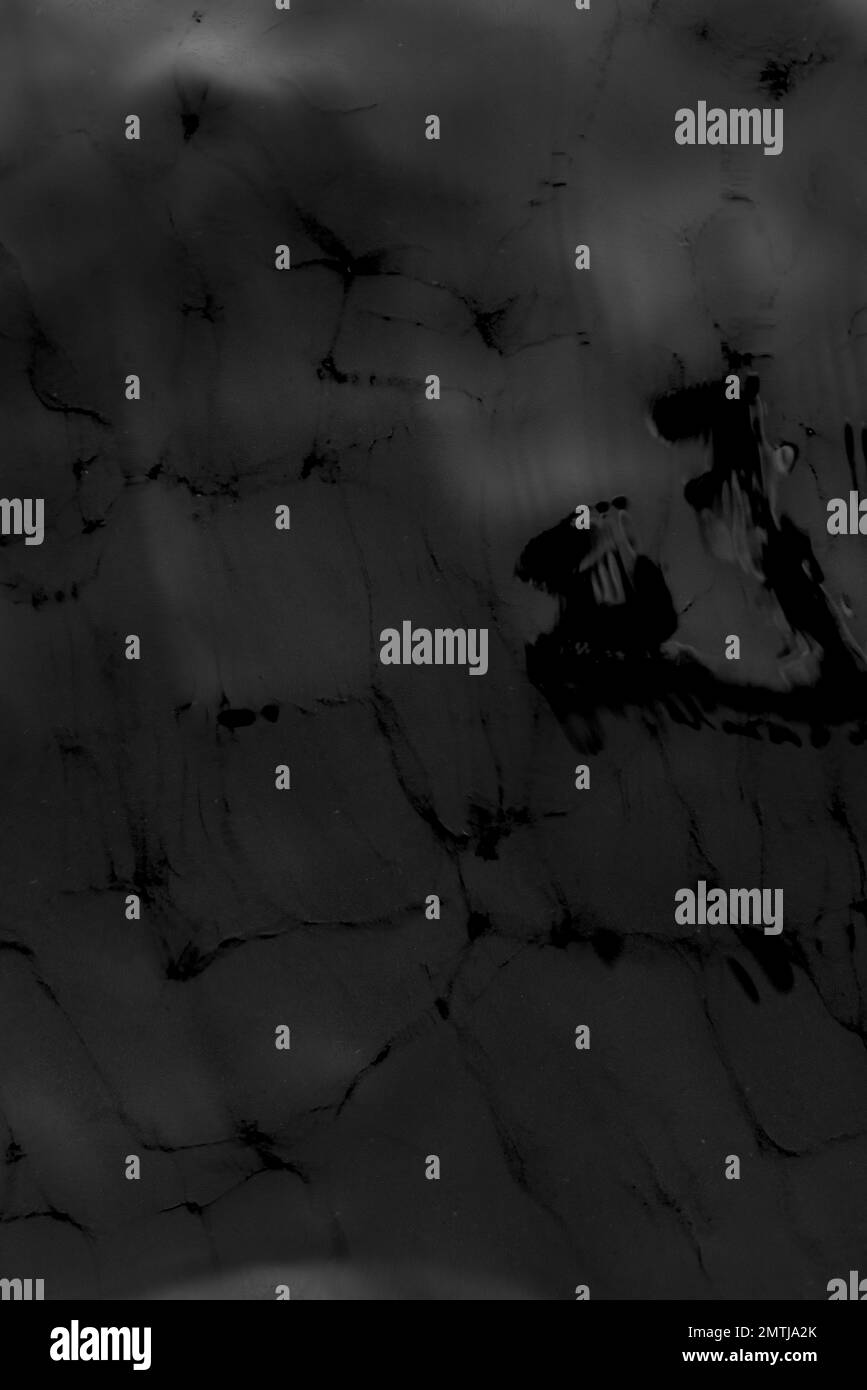 Schwarzweißfoto der Textur der Oberfläche der Bewegung von Wasserwellen auf einem grauen Boden. Der Hintergrund ist dunkel. Stockfoto