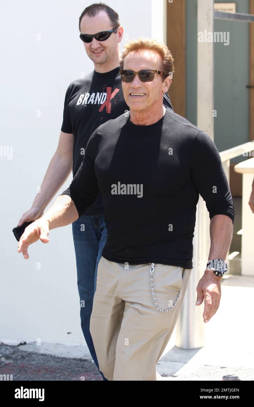 Arnold Schwarzenegger blickt auf tof The World zurück, als er am 30. Juli 2011 im Café Roma in Beverly Hills mit seinem Sohn Patrick zu Mittag isst, der mit der Paparazzi-Aufmerksamkeit, LA, CA, weniger als behaglich aussieht. Stockfoto