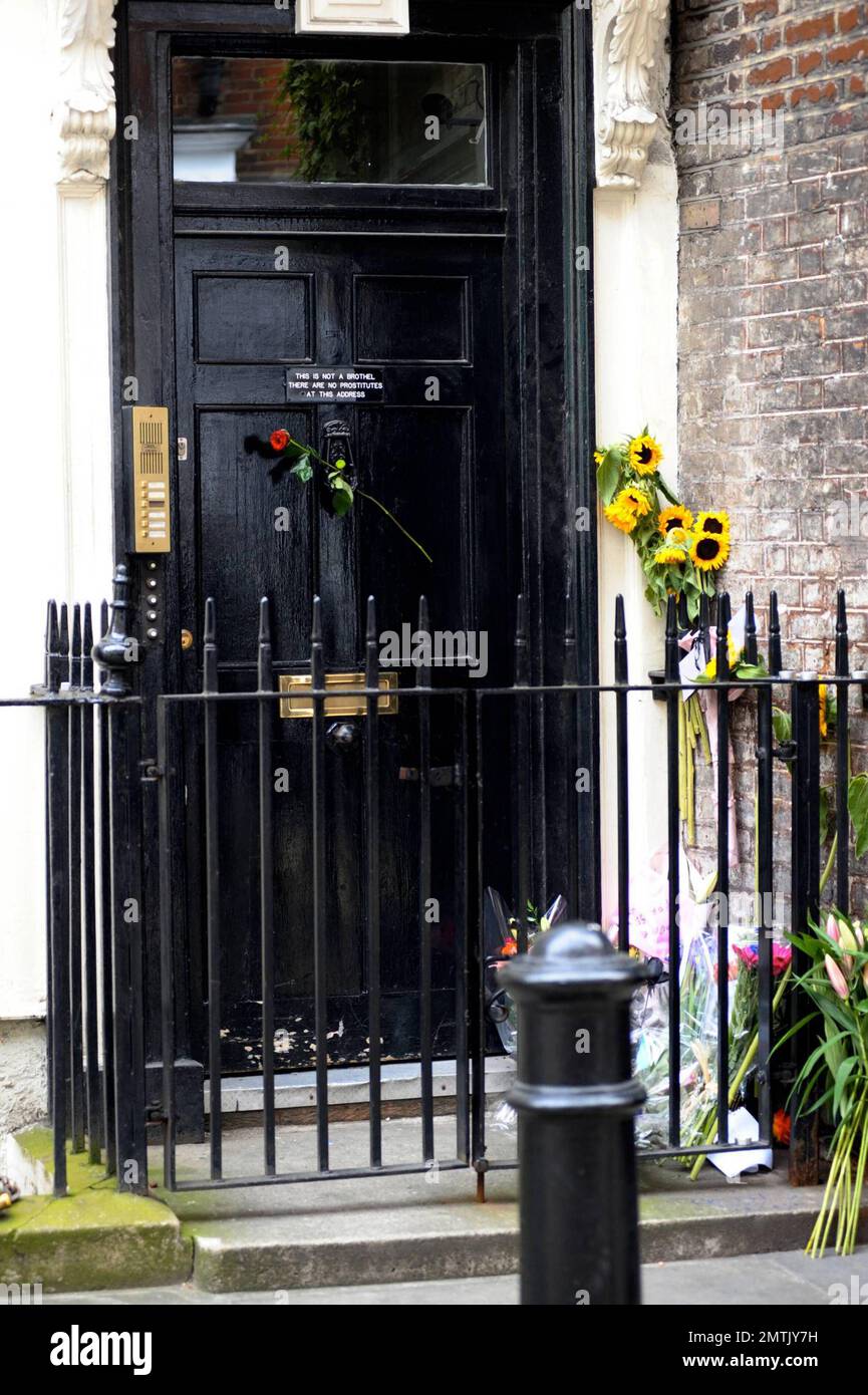 Fans haben Gedenkblumen vor dem Haus des Künstlers Sebastian Horsley platziert, wo er gestern tot aufgefunden wurde, wegen einer vermuteten Überdosis Heroin. Das Haus hat auch ein seltsames Schild an der Tür, auf dem steht "Dies ist kein Bordell. Hier gibt es keine Prostituierten." Die Leiche von Horsley, 47, die einst im Namen der Kunst gekreuzigt wurde, wurde von einer Freundin gefunden. Sein Tod kommt nur wenige Tage nach einem Stück „Dandy in the Underworld“, das auf seinen eigenen Memoiren basiert und im Soho Theatre eröffnet wurde. London, Großbritannien. 6/18/10. . Stockfoto