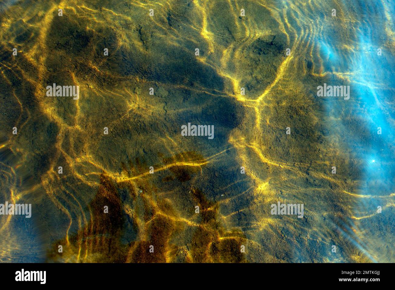 Abstraktes Foto der Textur der Reflexion von Licht von der Oberfläche der Wellen des durchsichtigen Lichtwassers in Bewegung in hellen Gelbtönen. Stockfoto