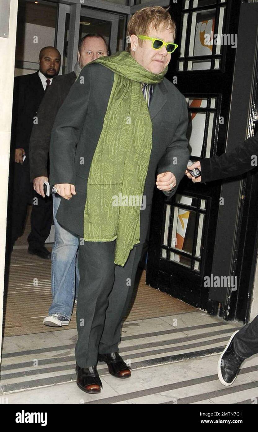 Sir Elton John Dons hat eine grüne Sonnenbrille und einen grünen Schal