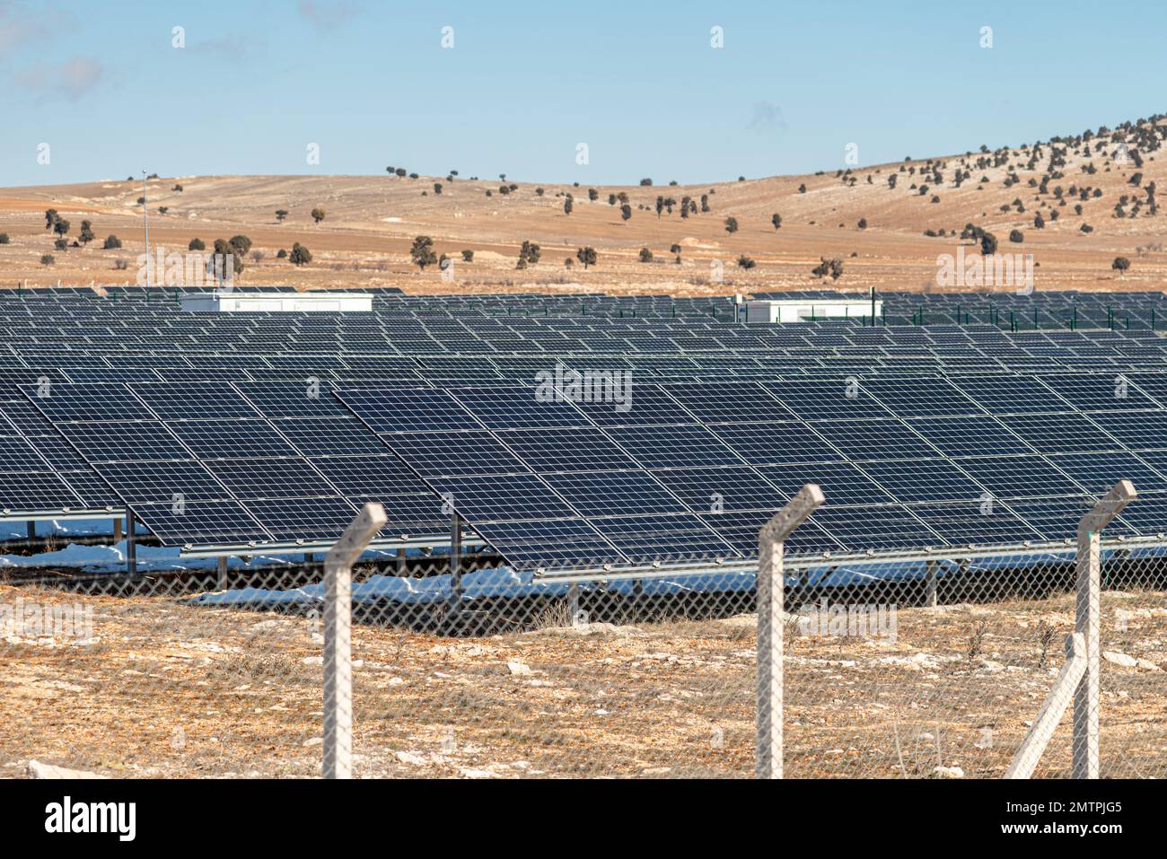 Solarfeld mit eingezäunten Sonnenkollektoren bei Sonnenuntergang Stockfoto