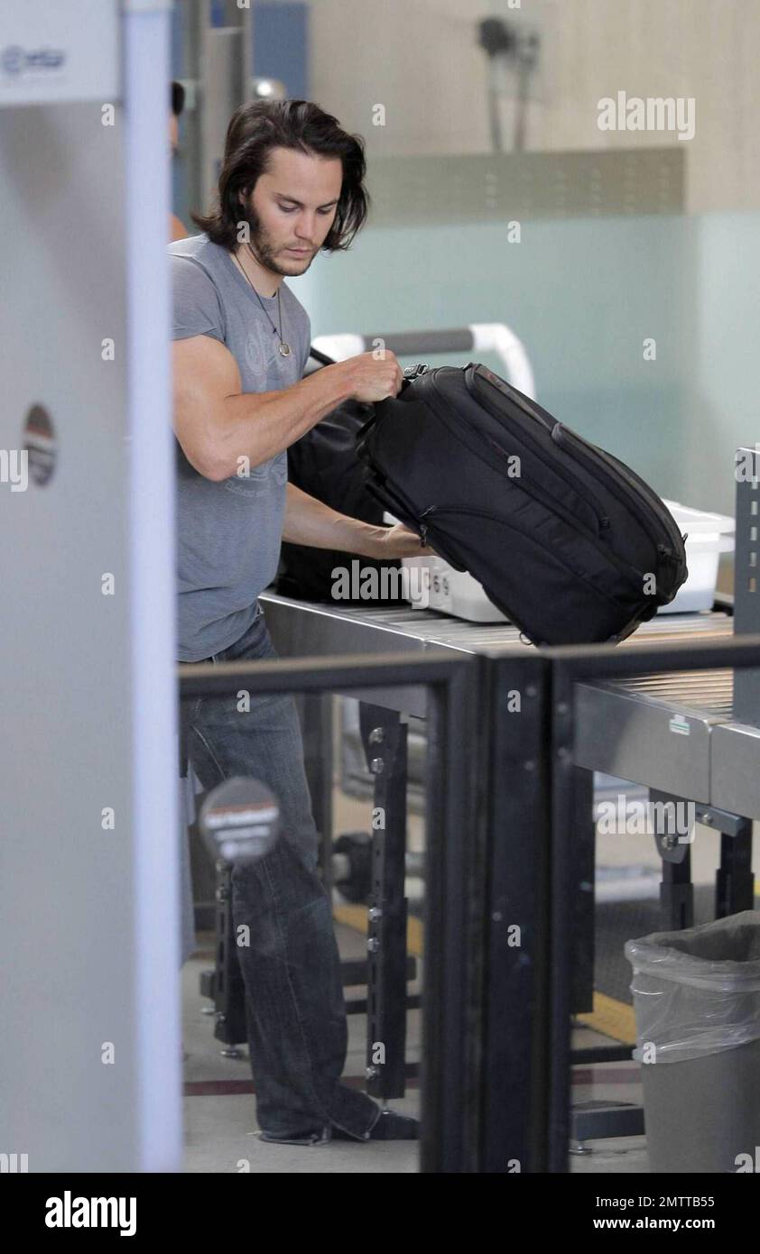 Taylor Kitsch schleppt seine eigenen Taschen auf dem Weg durch LAX, um einen Flug zu erwischen. Der X-Men Schauspieler trug eine Lederjacke und einen Hut, musste aber einige Schichten für die Sicherheitskontrolle ausziehen. Los Angeles, Ca. 6/2/09. . Stockfoto