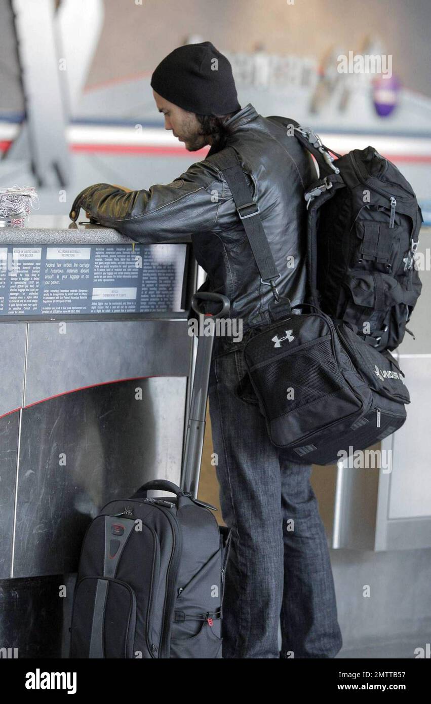 Taylor Kitsch schleppt seine eigenen Taschen auf dem Weg durch LAX, um einen Flug zu erwischen. Der X-Men Schauspieler trug eine Lederjacke und einen Hut, musste aber einige Schichten für die Sicherheitskontrolle ausziehen. Los Angeles, Ca. 6/2/09. Stockfoto