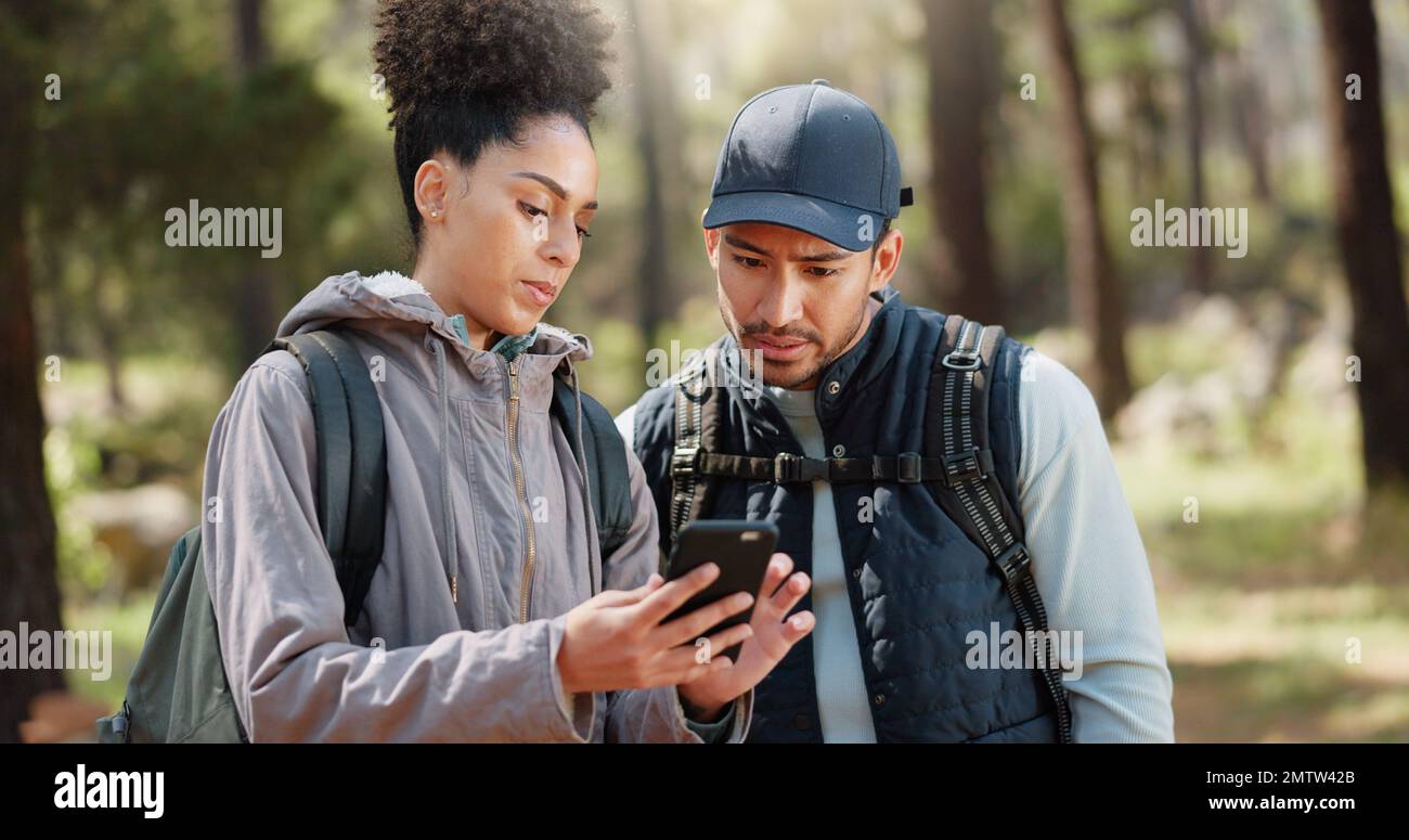 Wandern, Smartphone und Reisepaar mit Standortsuche, Online-Reiseführer oder Naturreiseplanung zusammen in einem Wald auf 5G Netzwerk. Rucksack Stockfoto